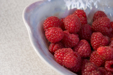 Big ripe raspberries are laying on the  table covered with white tablecloth