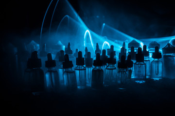 Vape concept. Smoke clouds and vape liquid bottles on dark background. Light effects. Useful as background or electronic cigarette advertisement.