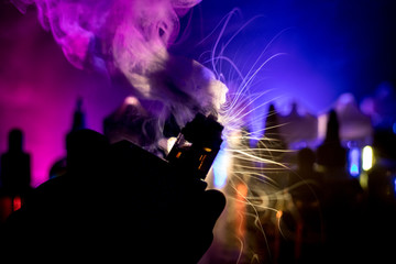 Vape concept. Electronic Cigarette vape explosion. Smoke clouds and vape liquid bottles on dark...