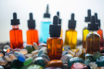 Vape concept. Beautiful colorful vape liquid glass bottles outdoor on stones. Useful as background...