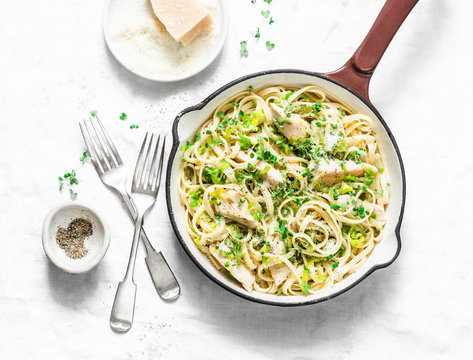 Chicken, leek, linguine pasta carbonara in a frying pan on a light background, top view. Flat lay