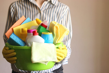  cleaning products in the basket in the hands of a young housewife.