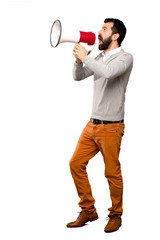 Handsome man shouting through a megaphone over isolated white background