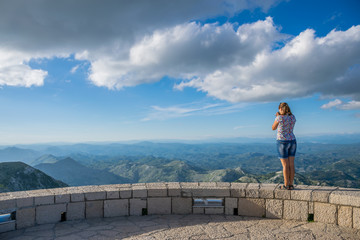 Cute young girl photographer admiring scenery from the viewpoint.