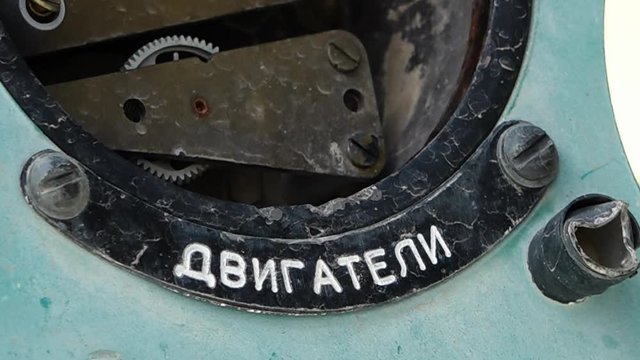 A steady, extreme close up shot of some metal parts that have white Russian engravings on them. 