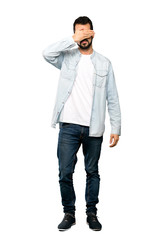 Fototapeta premium Full-length shot of Handsome man with beard covering eyes by hands. Do not want to see something over isolated white background