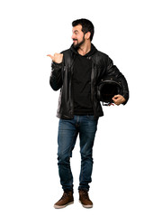 Naklejka premium Full-length shot of Biker man pointing to the side to present a product over isolated white background