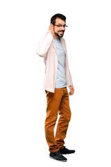 Full-length shot of Handsome man with beard listening to something by putting hand on the ear over isolated white background