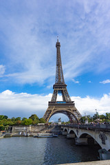Eiffel Tower with view of Seine river and the bridge in cloudy blue sky day in Paris, France