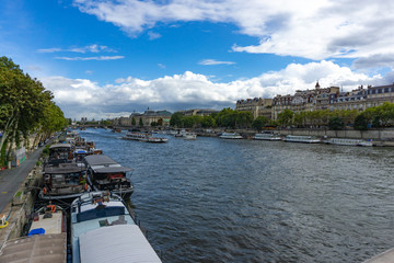 Fototapeta na wymiar Landscape view of Seine river with cruises and boat tour with Paris city in the background in cloudy blue sky day