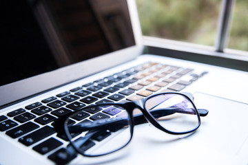 Fototapeta premium thee keyboard of a laptop with a glasses on it