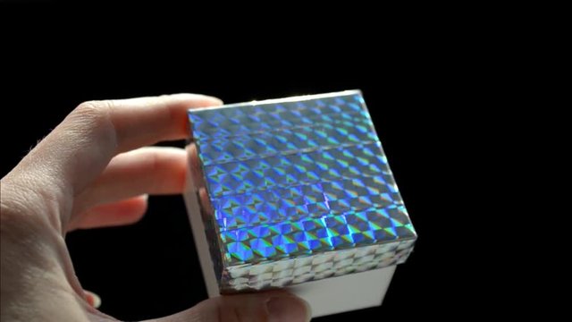 White gift box with rainbow scotch cover in hand, DIY idea, on black background