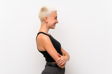 Teenager girl with short hair over white wall in lateral position