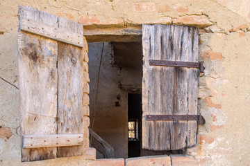 Close-up of an old damaged window of an abandoned house with wooden shutters and brick wall, Piedmont, Italy