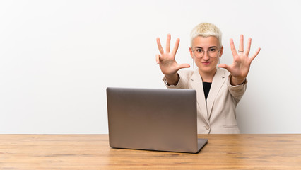 Teenager girl with short hair with a laptop counting nine with fingers