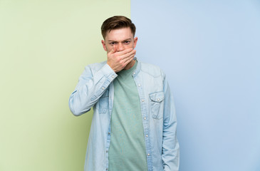 Redhead man over colorful background covering mouth with hands