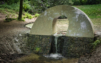 pond with small waterfall in green forest