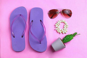 Beach purple beach flip flops, aviator sunglasses, seashell bracelet and succulent cacti cactus on a pink background. Summer colorful  travel beach flat lay