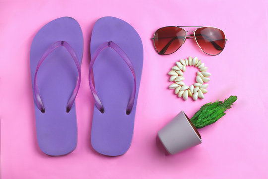 Beach purple beach flip flops, aviator sunglasses, seashell bracelet and succulent cacti cactus on a pink background. Summer colorful  travel beach flat lay