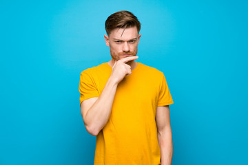 Redhead man over blue wall thinking