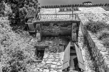 Black and white photo of the facade of an old house in a narrow street in the old center of the  picturesque medieval village of Eze