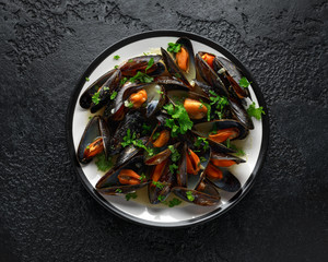 Mussels with white wine, garlic, lemon and herbs in a plate, rustick background. Seafood.