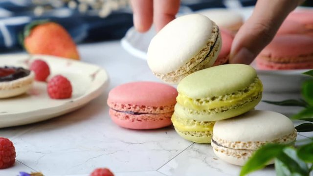 Slow-motion hand pick Colorful French macarons cakes desert set on party table.