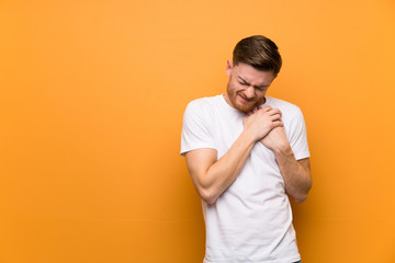 Redhead man over brown wall having a pain in the heart