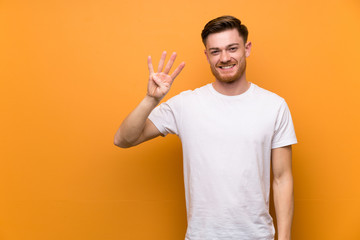 Redhead man over brown wall happy and counting four with fingers