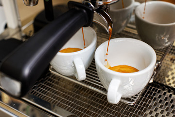Coffee brewing in coffee machine. Espresso pouring in two cups.