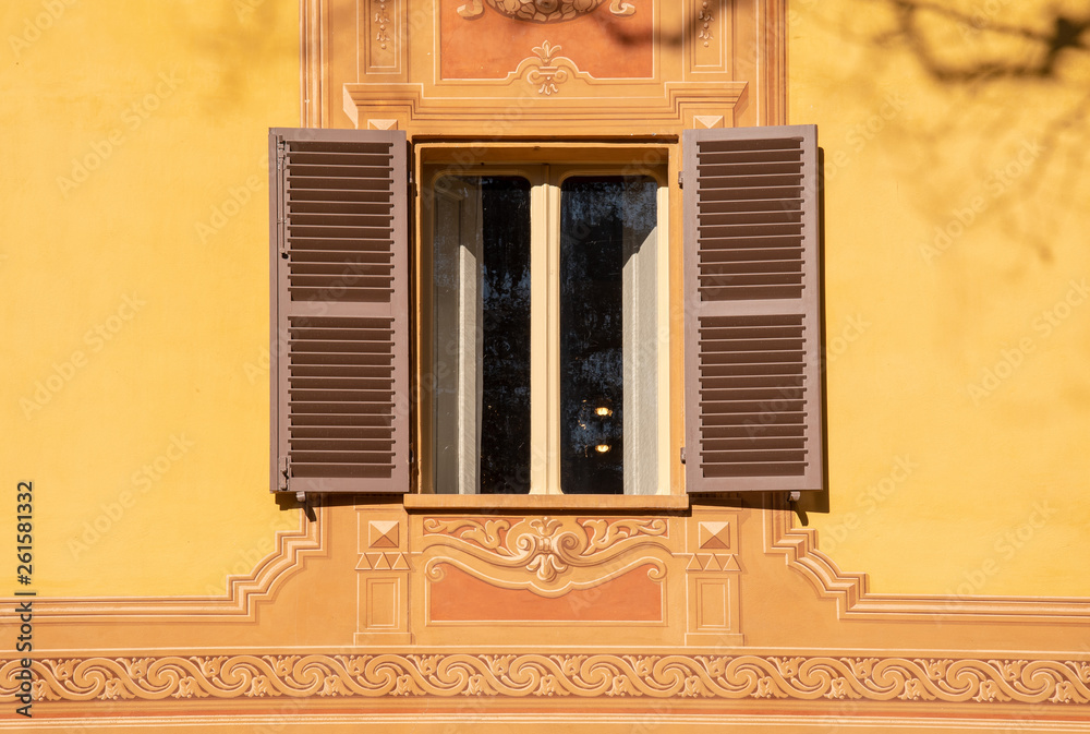 Wall mural close-up of a window on the decorated façade on an old villa in warm colors, piedmont, italy