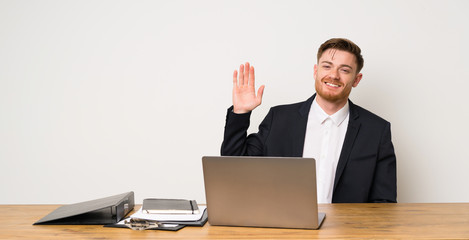 Businessman in a office saluting with hand with happy expression