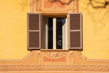 Close-up of a window on the decorated façade on an old villa in warm colors, Piedmont, Italy