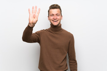 Blonde man over isolated white wall happy and counting four with fingers