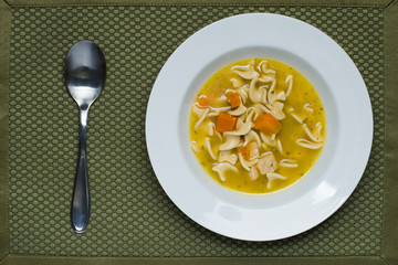 Chicken noodle soup and a spoon.