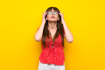 Young woman over yellow wall with headache