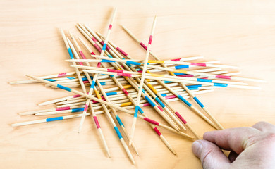 Obraz premium player picks up a stick in Mikado game on board