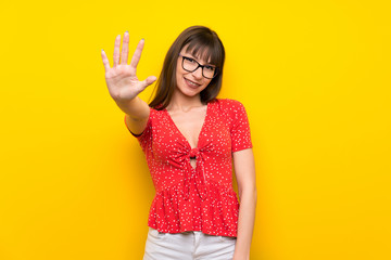 Young woman over yellow wall counting five with fingers