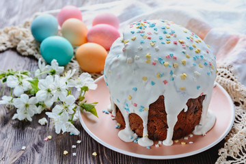 Homemade Easter cake next to painted eggs and a sprig of blossoming fruit tree