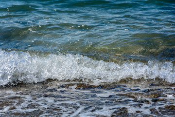 Navy sea wave with bubbles of water runs ashore