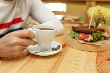Man hold white cup of coffee at sandwich background