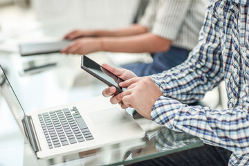 close up.business man with a smartphone sitting at his Desk