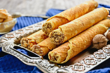 Delicious homemade wafer rolls filled with condensed milk and chopped walnuts are on a tin tray