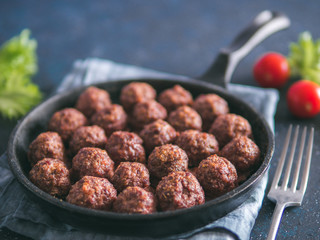 Homemade roasted beef meatballs in cast-iron skillet on dark blue background. Copy space for text. Shallow DOF
