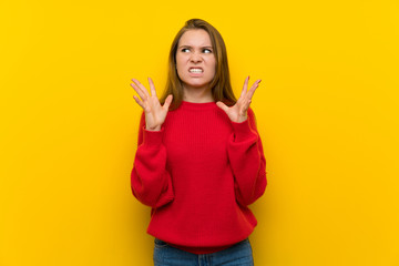 Young woman over yellow wall frustrated by a bad situation