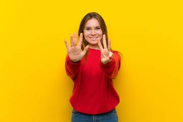 Young woman over yellow wall counting eight with fingers