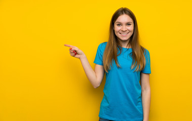 Young woman with blue shirt pointing finger to the side