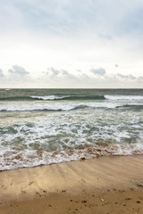 Fototapeta na wymiar Blue and green waves with white foam on sandy beach. Black Sea, Evpatoria, Crimea, Russia. Travel, wacation concept. Text copy space.