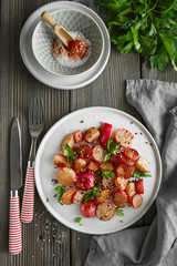 Beautiful roasted radishes served with parsley and sesame seeds in a plate on wooden rustic background.