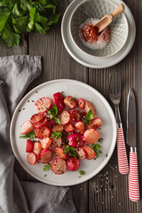 Beautiful roasted radishes served with parsley and sesame seeds in a plate on wooden rustic background.